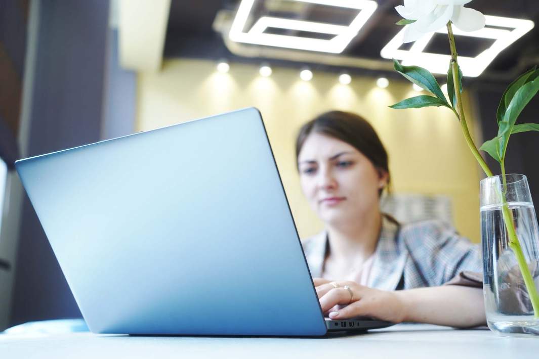 женщина работает в ноутбуке цветок в вазе на столе кафе