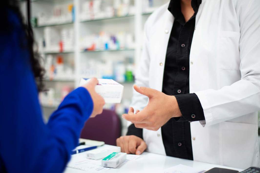 женщина отдает мужчине лекарство в аптеке