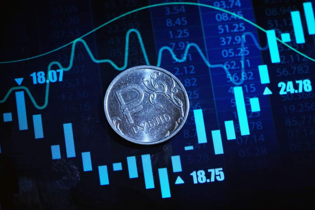 Монеты рубли на фоне графиков