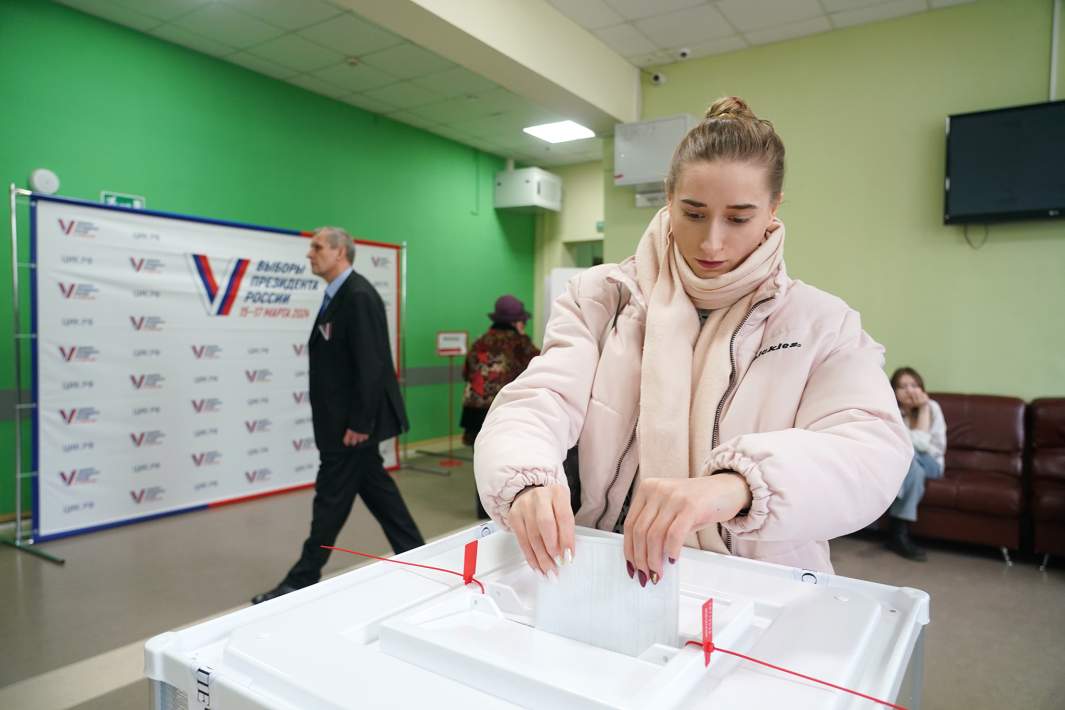 Девушка голосует на выборах президента России на избирательном участке