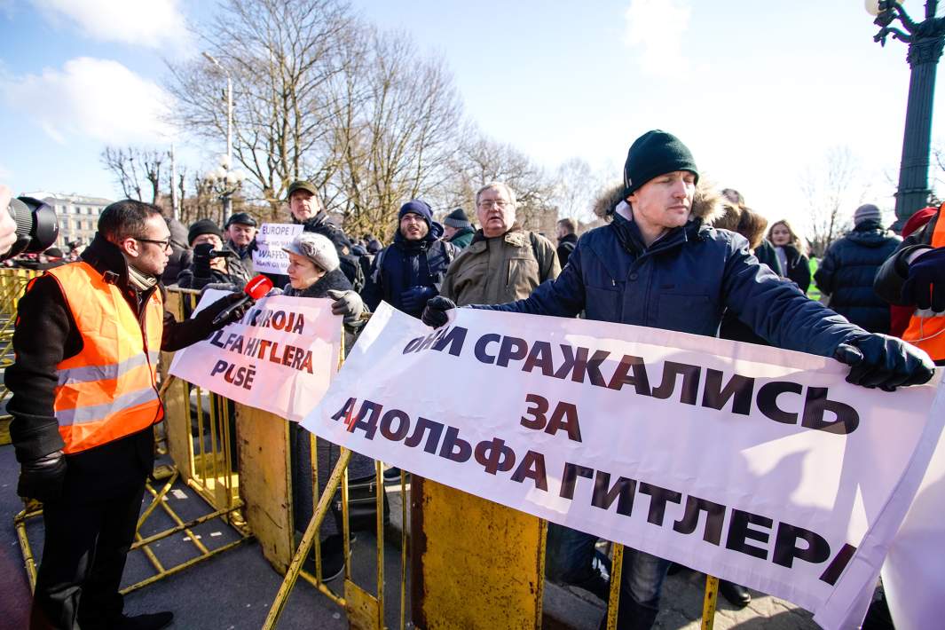 Представители антифашистских организаций держат плакаты с надписью "Они сражались за Адольфа Гитлера" на акции протеста во время марша бывших латышских легионеров СС и их сторонников в Риге