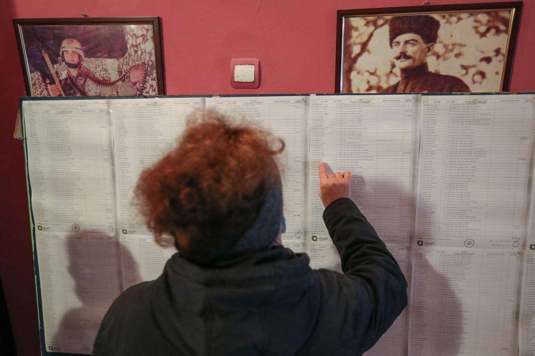 женщина смотрит список кандидатов на выборы в парламент Грузии