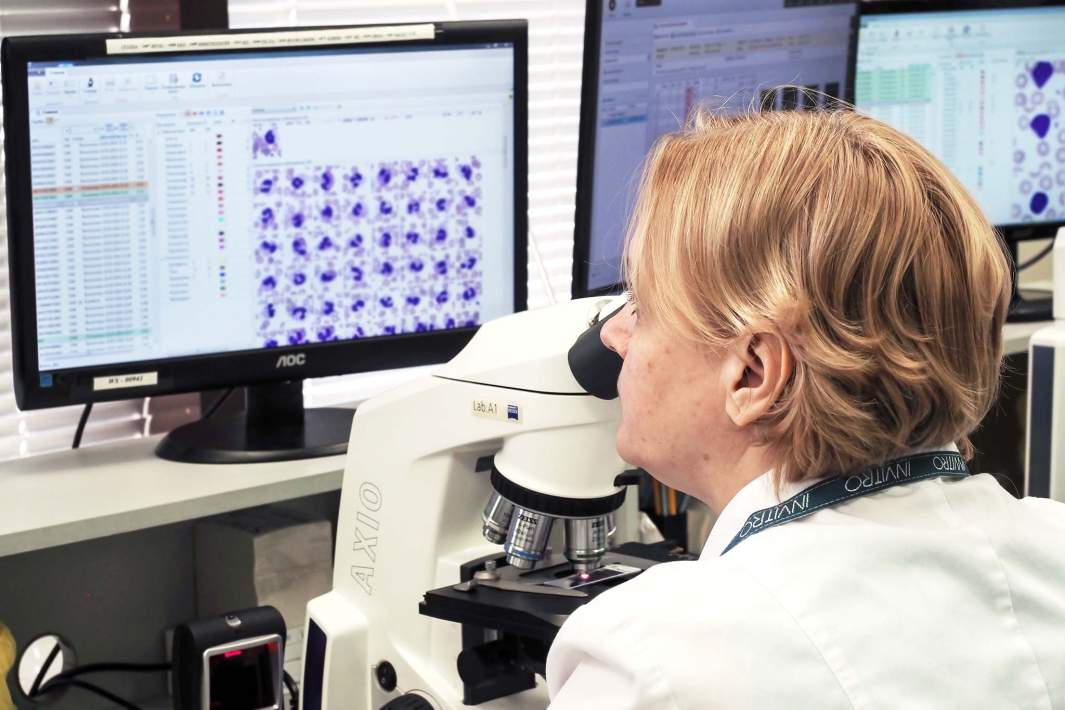 biologist examines samples using a microscope and computer