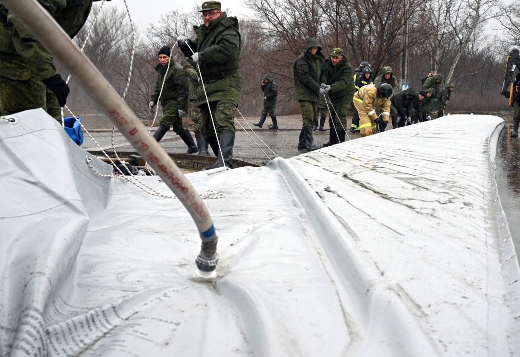 Сотрудники МЧС и военнослужащие устанавливают водоналивную дамбу, доставленную в Оренбург