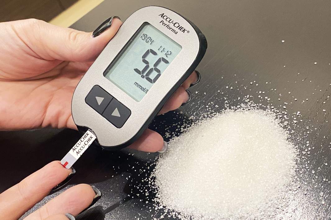 глюкометр показывает значение содержания сахара в крови горстка сахара на столе