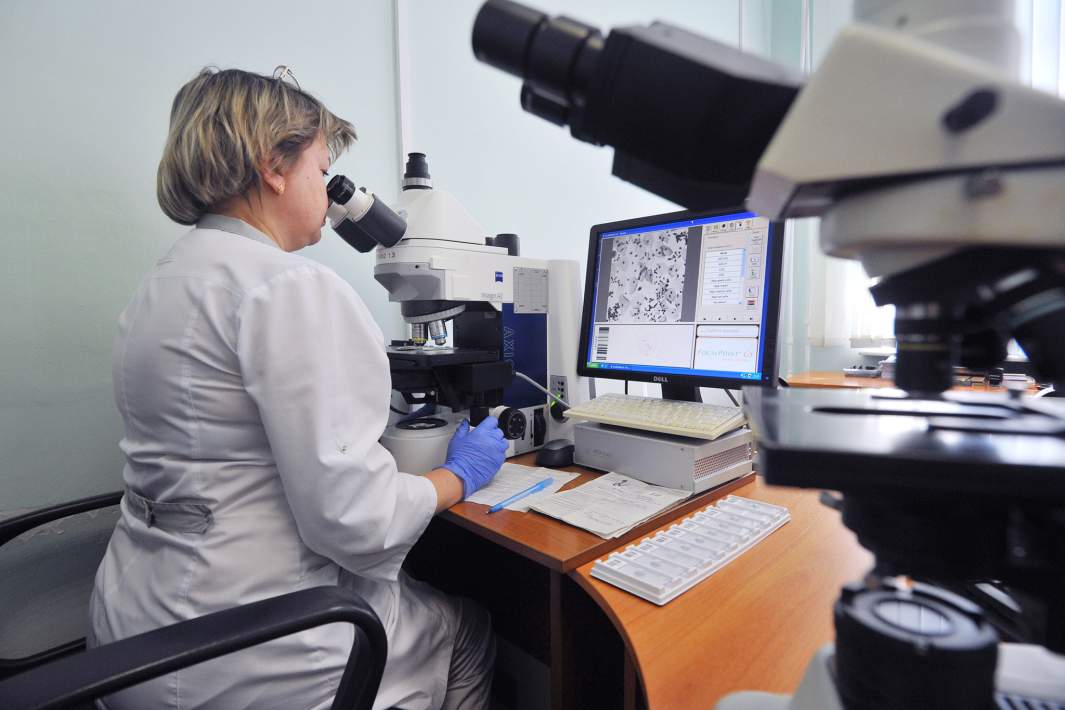 врач смотрит в микроскоп и изучает препарат