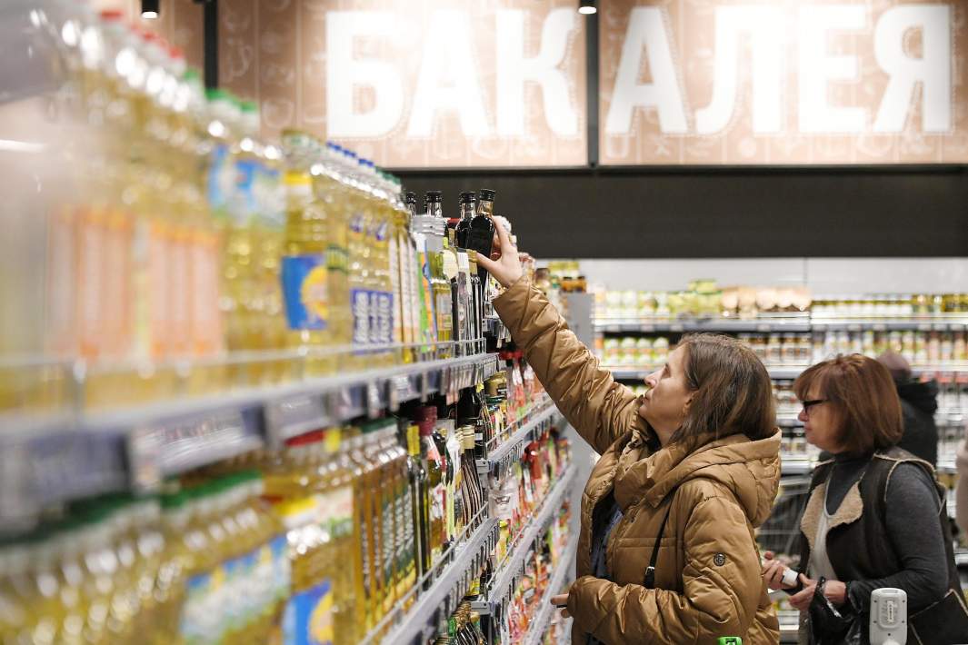 женщина выбирает себе масло  на полке магазина