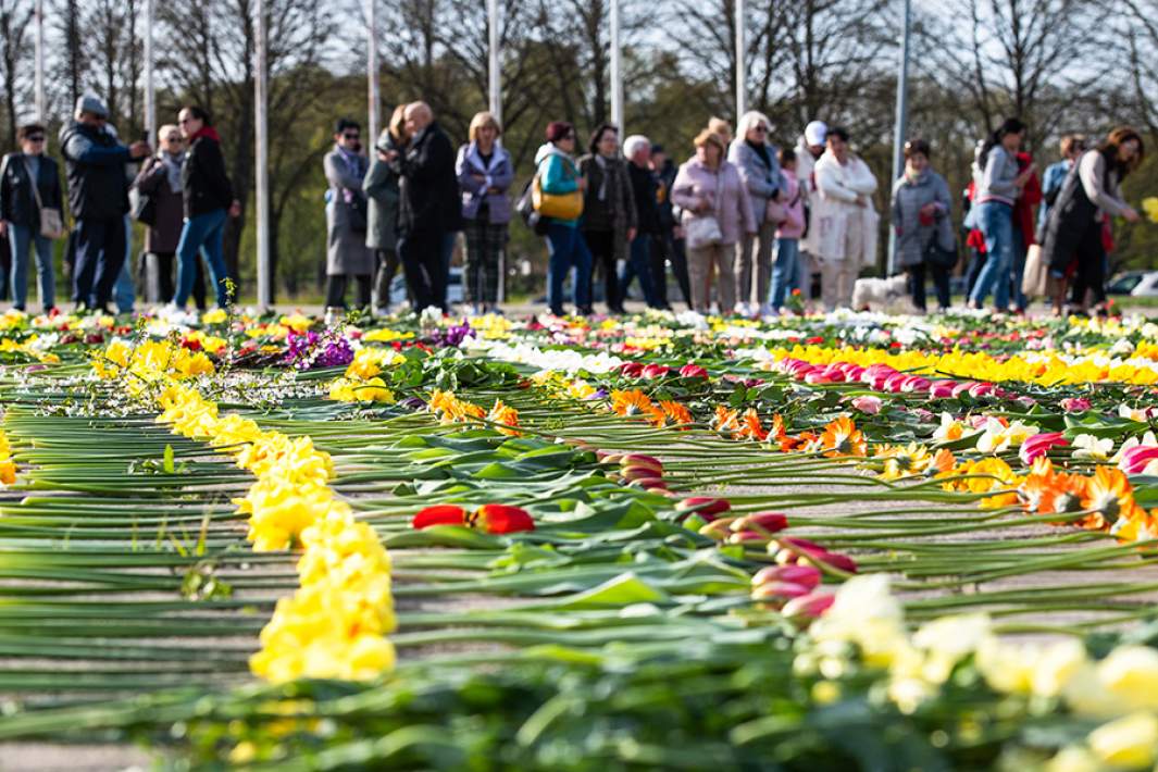 Жители Риги во время возложения цветов к памятнику Освободителям, Латвия, 9 мая 2022 года. Утром следующего дня все цветы были собраны бульдозером 