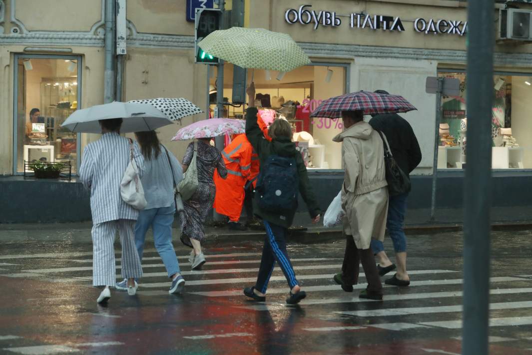 в москве тропический ливень люди с зонтами переходят дорогу