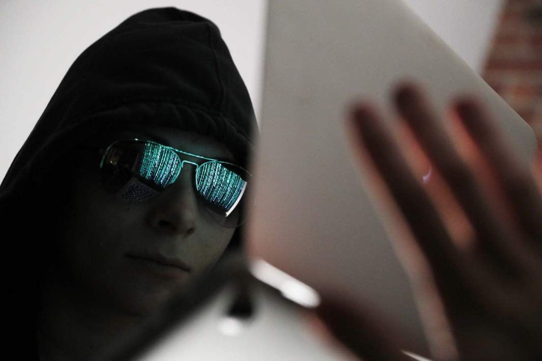 мошенник хакер смотрит в ноутбук