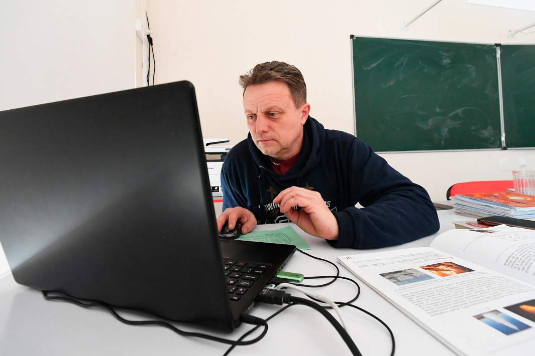 Учитель сидит за компьютером