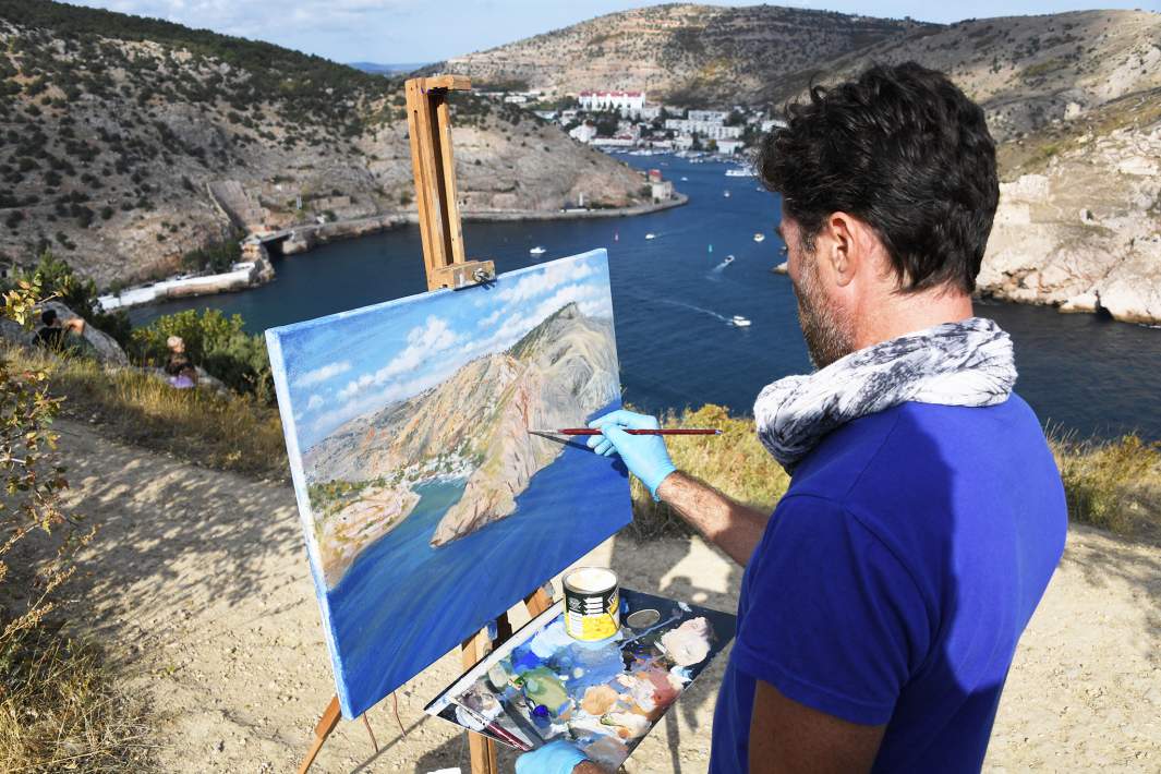 Человек пишет картину в горах море
