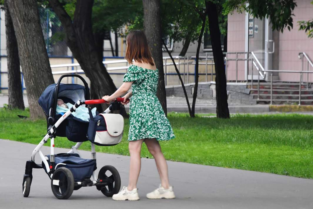 Девушка с ребенком и детской коляской во время прогулки