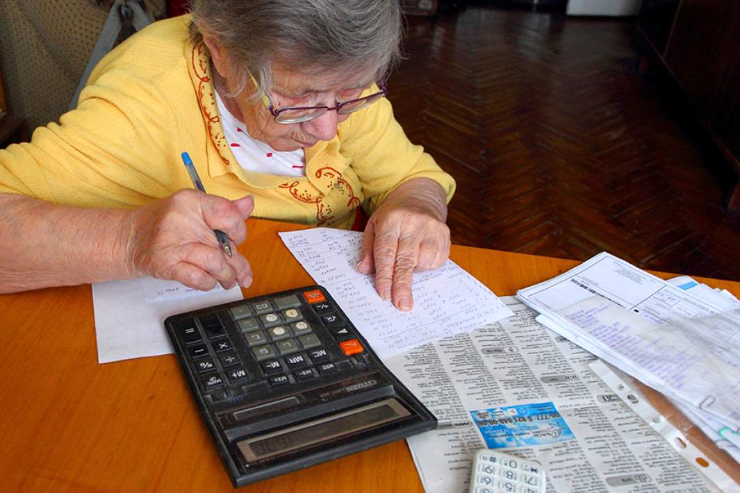 Пенсионерка проверяет счета за коммунальные услуги