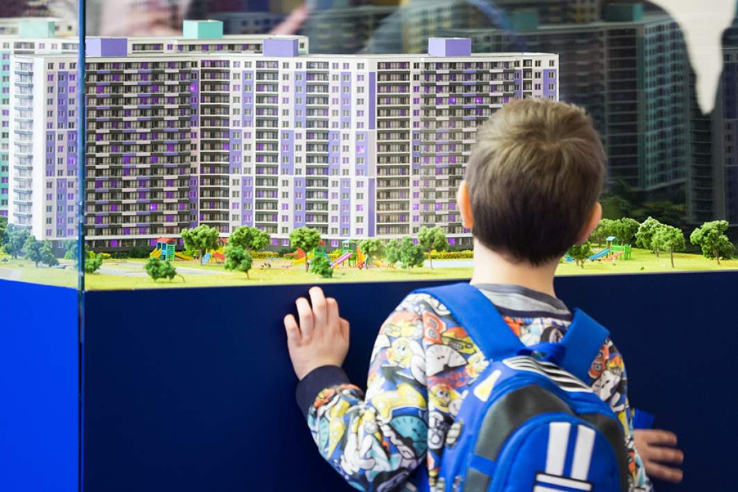 Ребенок рассматривает макет многоквартирного дома