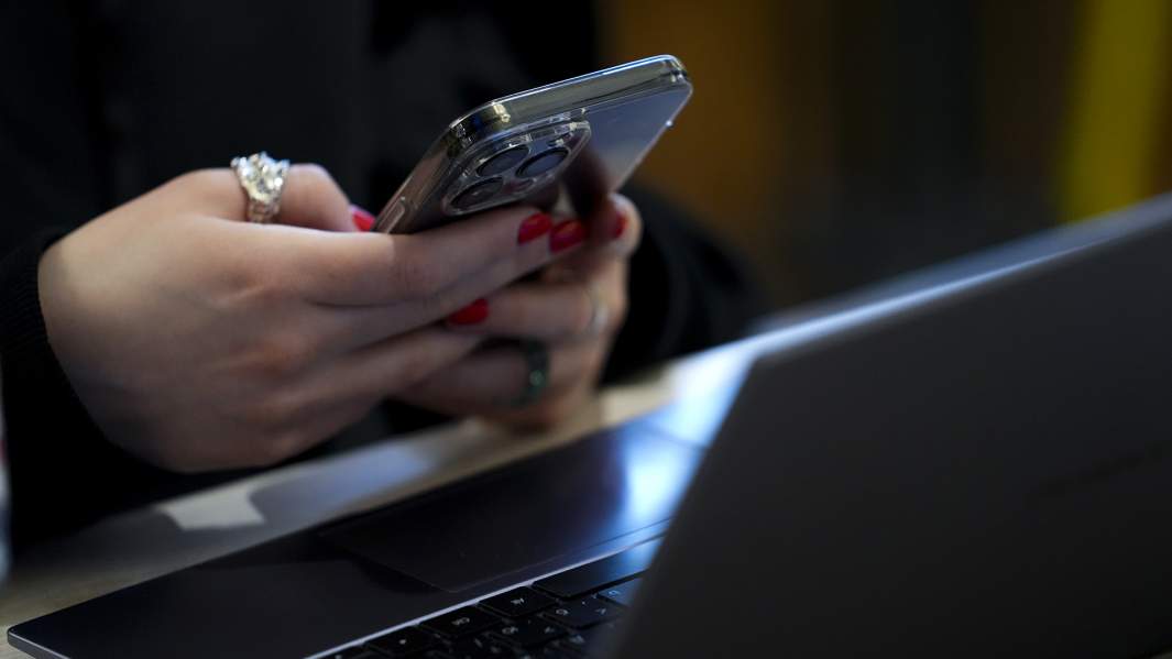 Девушка использует телефон с ноутбуком