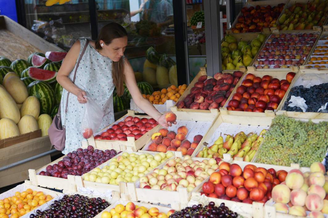 Девушка покупает овощи и фрукты на рынке