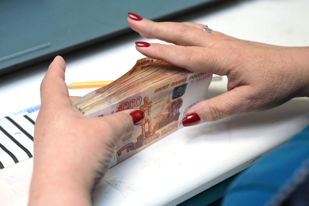 Сотрудница банка пересчитывает купюры номиналом в пять тысяч рублей