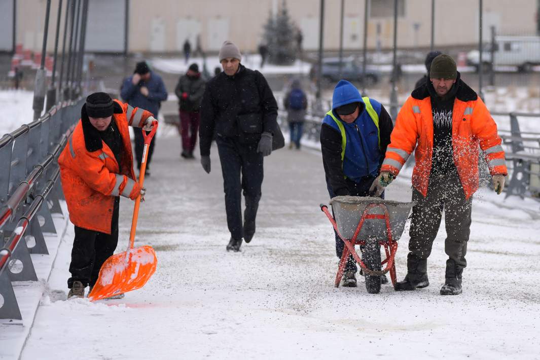 Сотрудники ЖКХ убирают снег на улице в Москве