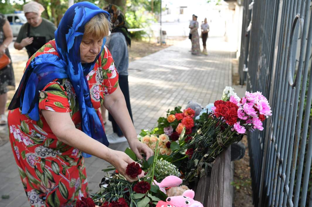 Женщина возлагает цветы к стихийному мемориалу в Учкуевке в день траура по погибшим в результате ракетной атаки Вооруженных сил Украины