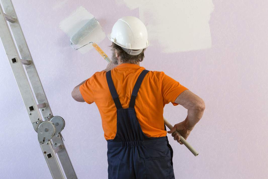 Маляр красит стену