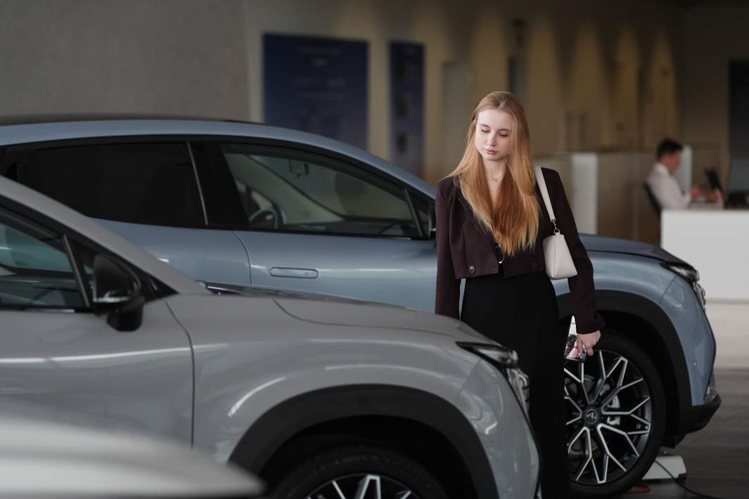 Девушка выбирает автомобиль в автосалоне