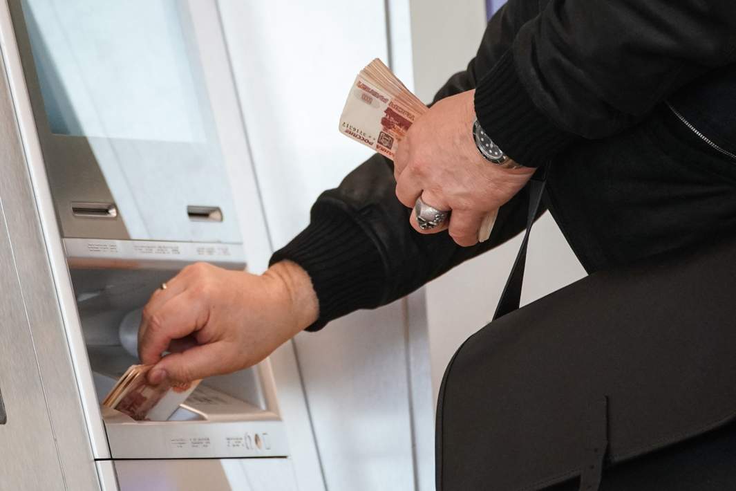 Мужчина кладет деньги в банкомат 