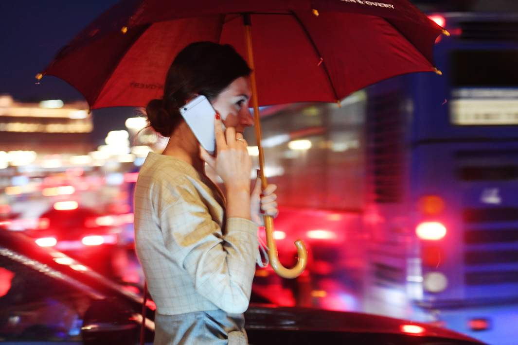 Девушка идет по улице и разговаривает по телефону во время дождя