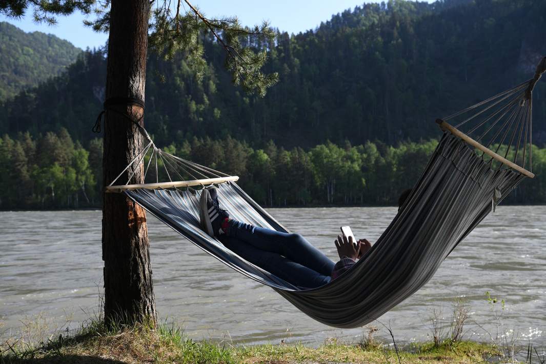 Отдыхающий лежит в гамаке на территории глэмпинга