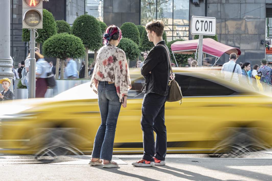 Такси проезжает на фоне людей 