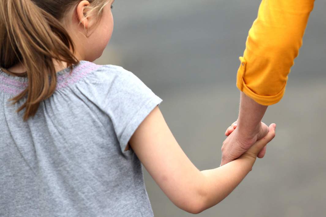 родитель держит ребенка за руку