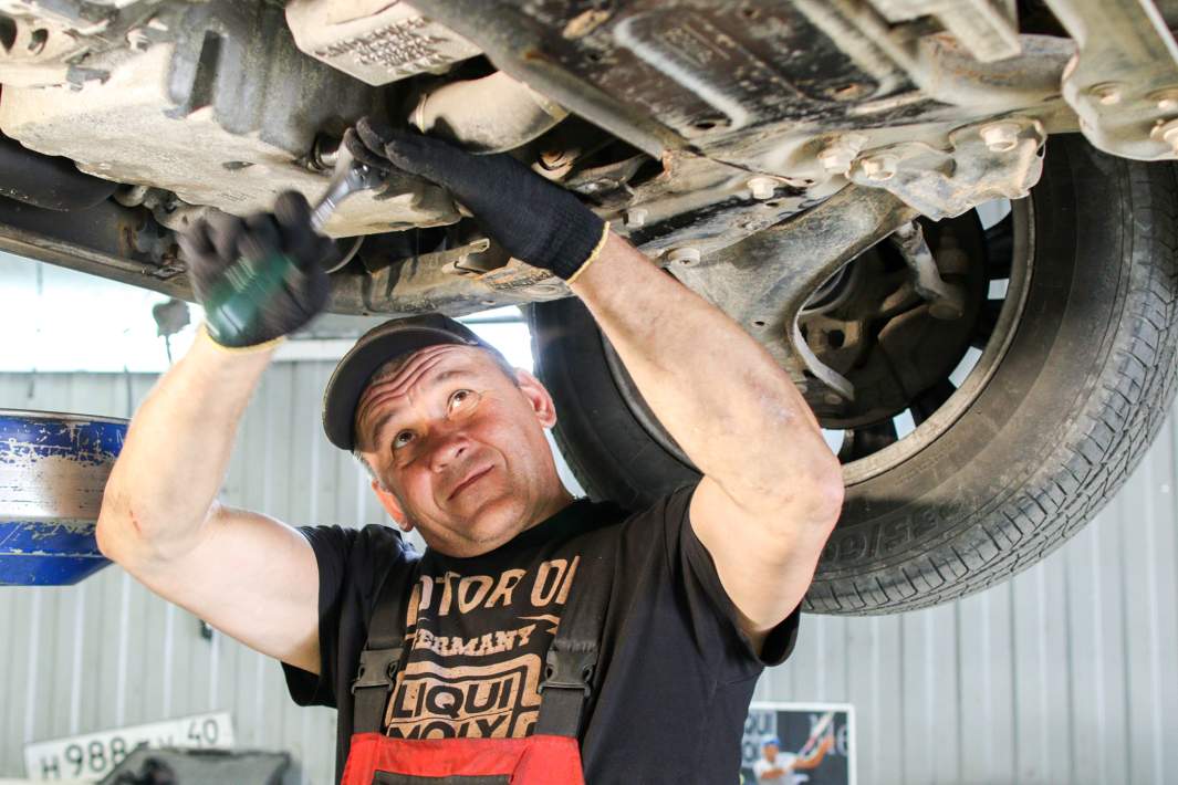 Автослесарь работает в сервисном центре автосалона