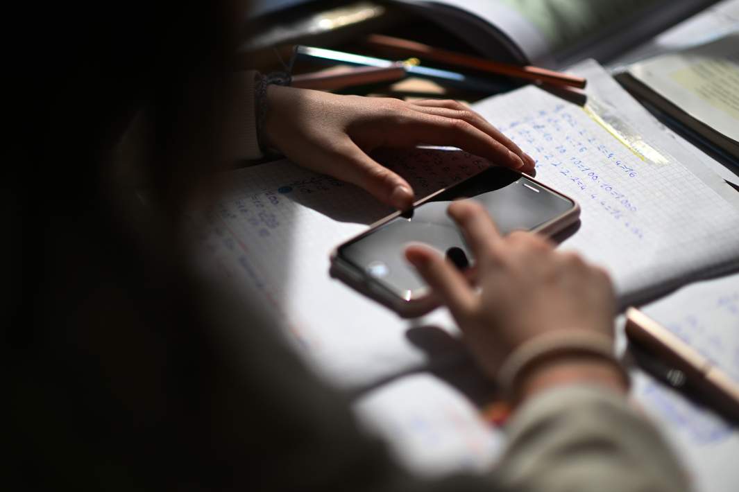 Ребенок смотрит в телефон пока делает уроки 