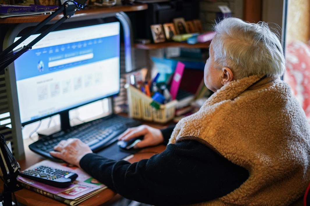 Женщина пенсионного возраста сидит за компьютером