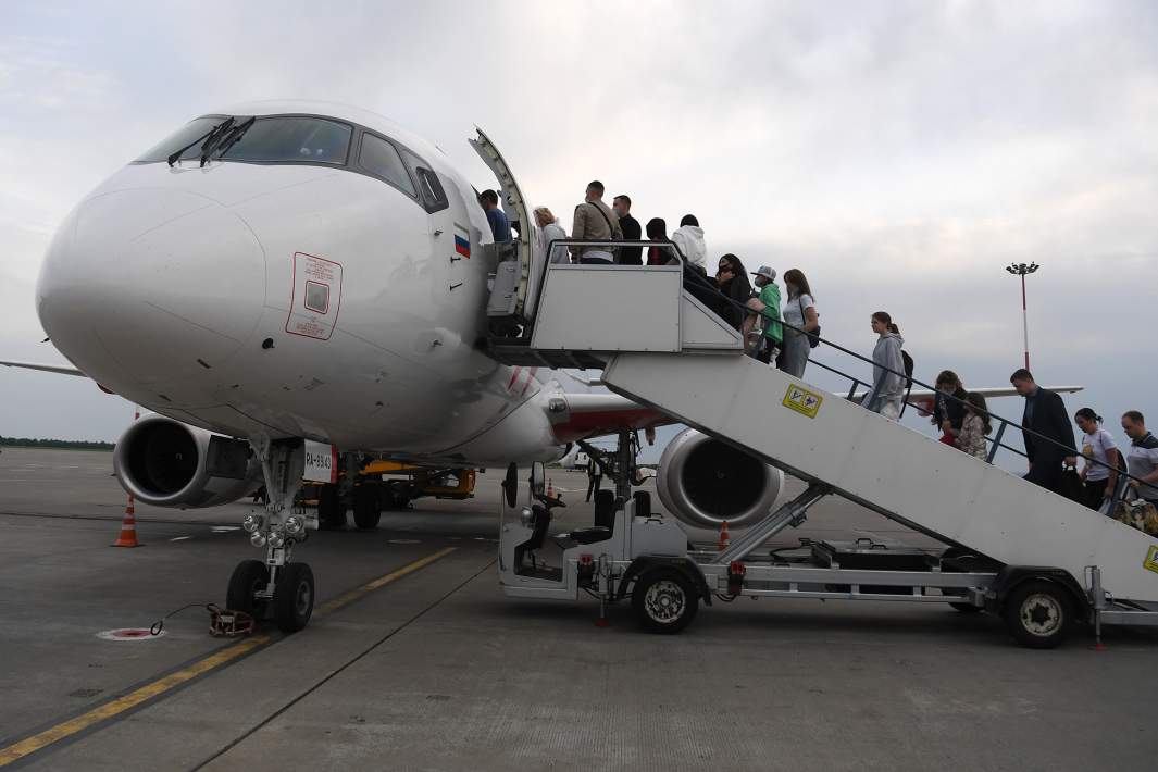 Пассажиры поднимаются по трапу на борт самолета