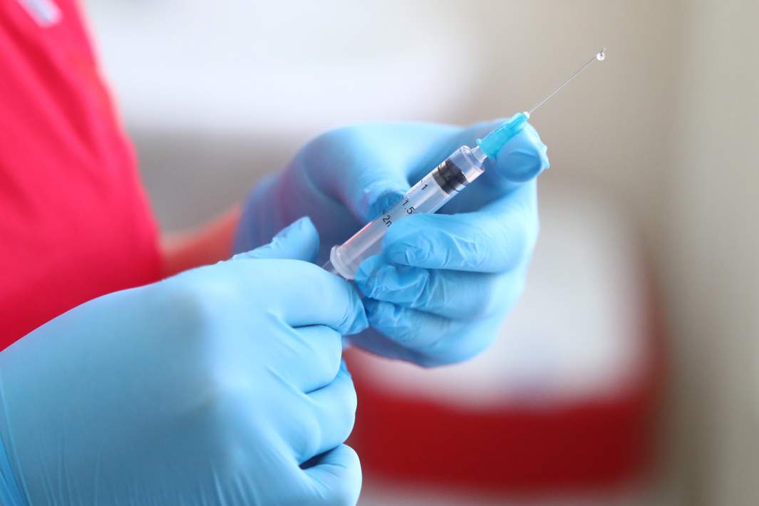 Медицинский работник держит шприц