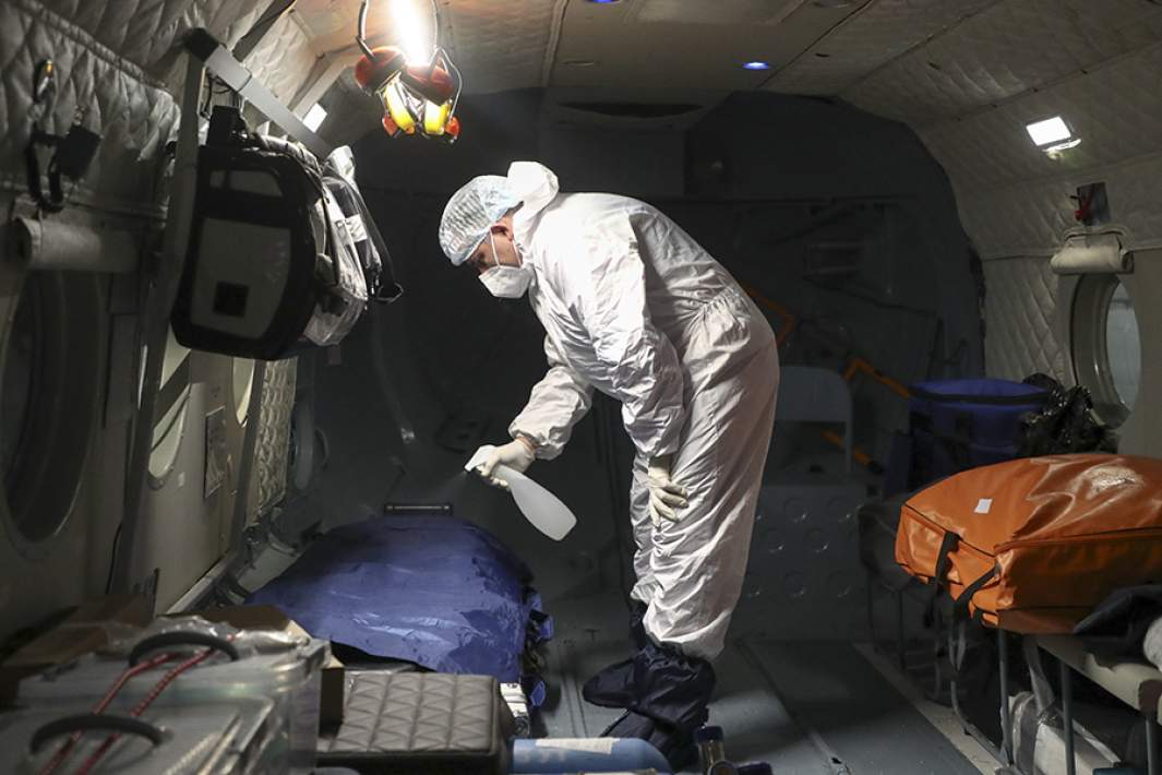 Сотрудник авиамедицинской бригады обрабатывает поверхности в вертолете