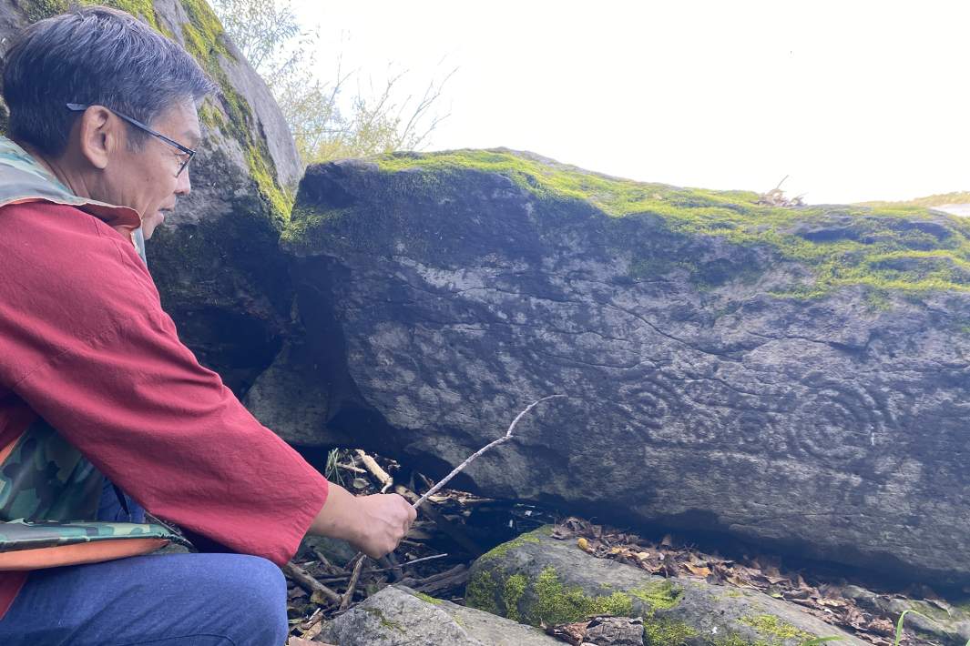 Нанаец Александр У демонстрирует один из петроглифов возле села Сикачи-Аля