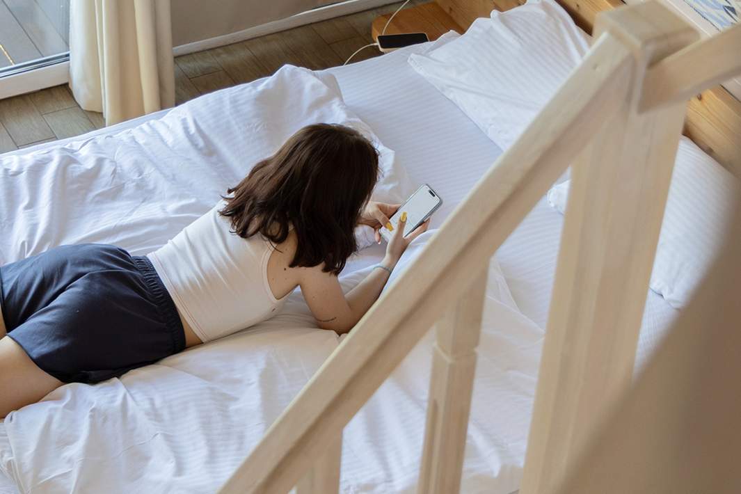 Девушка в деревянном коттедже загородного комплекса со смартфоном