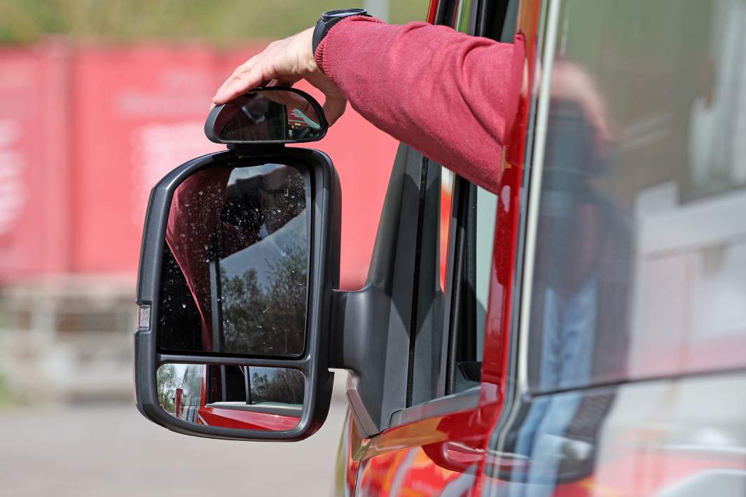 Водитель поправляет зеркало 