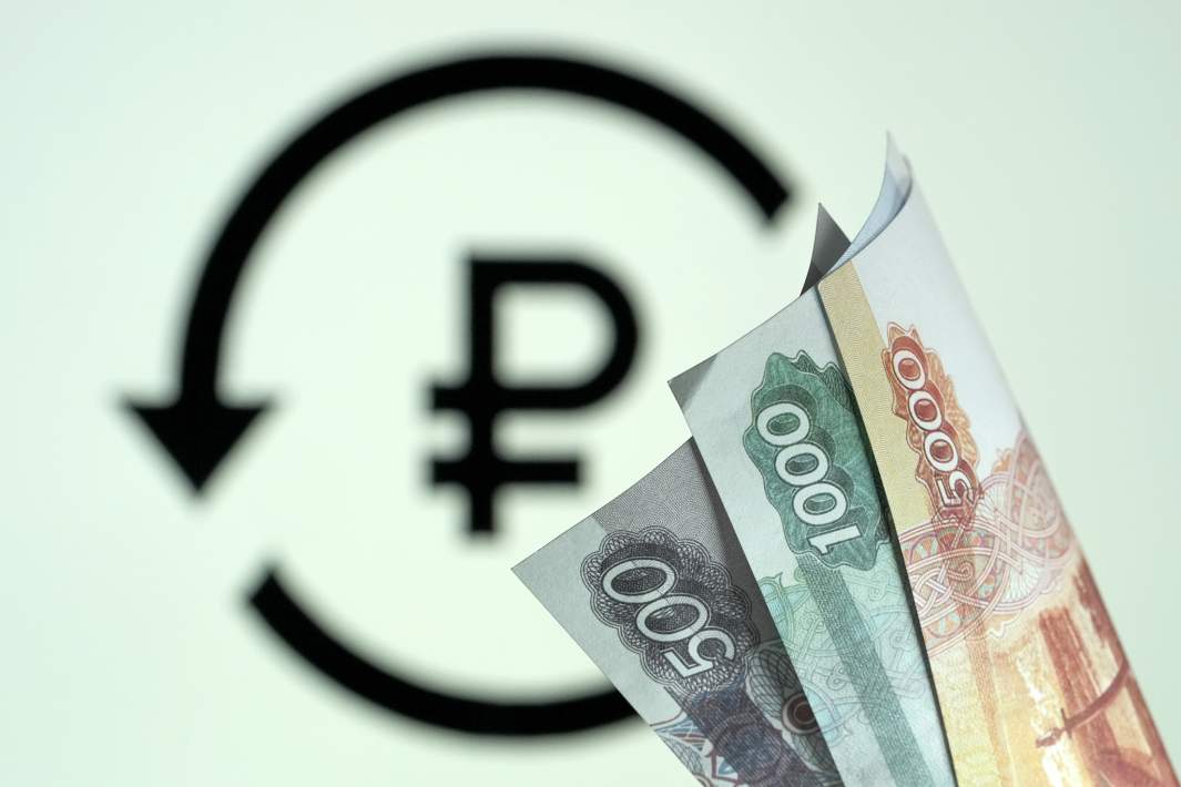 Рублевые купюры на фоне символа цифрового рубля 