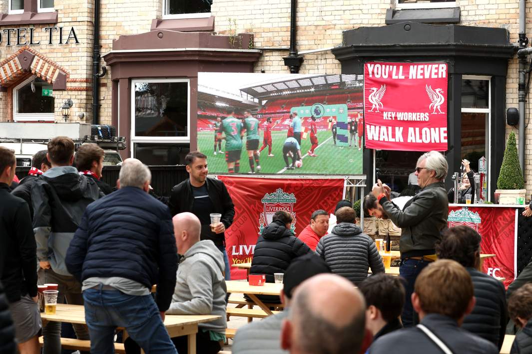 Болельщики смотрят матч на экране на улице