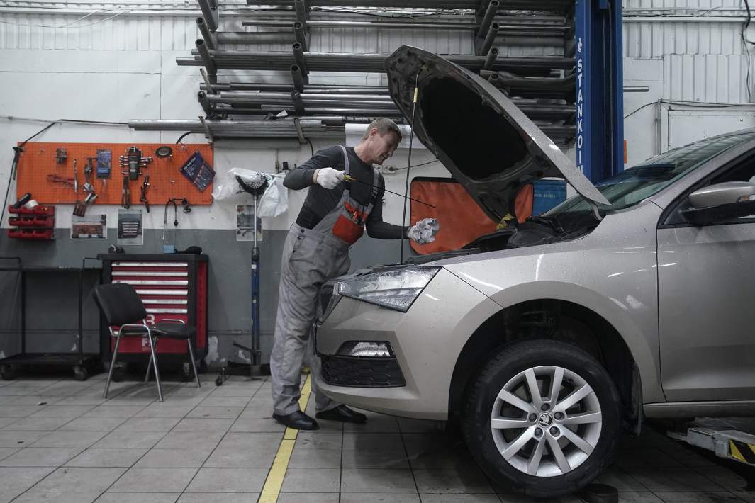 Автослесарь осматривает автомобиль