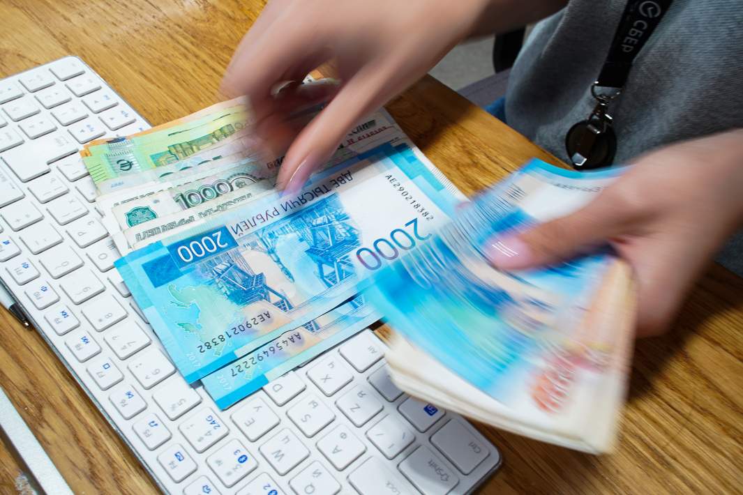 Сотрудник пересчитывает купюры различного номинала в одном из отделений банка