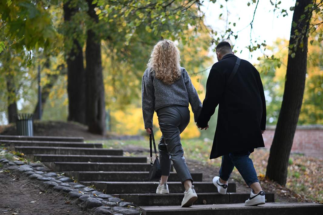 Мужчина и жензина держатся за руки в парке