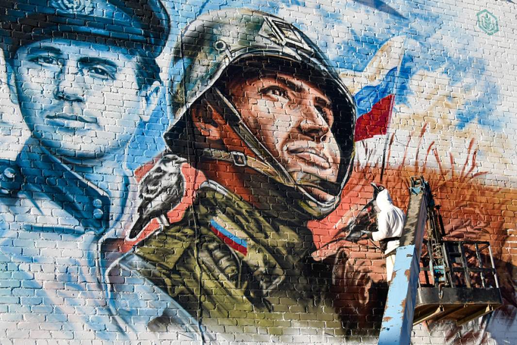 Художник рисует мурал с изображением Героев Отечества на здании школы