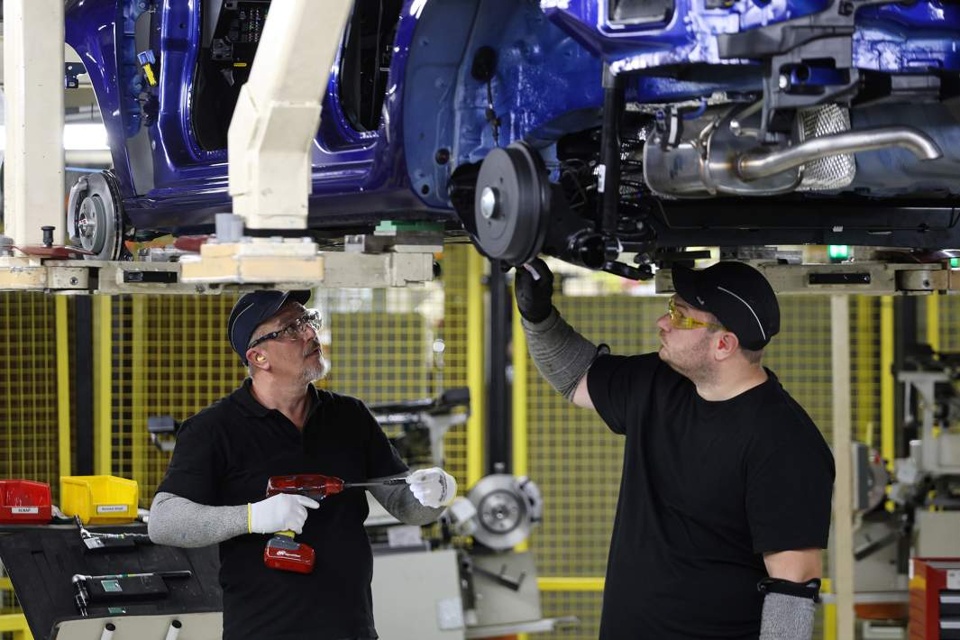 Рабочие собирают машины на заводе 