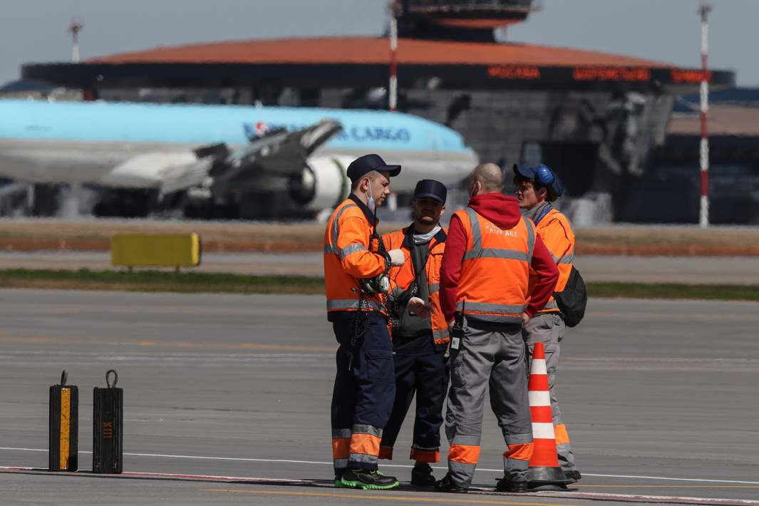 Сотрудники аэропорта на фоне самолета 