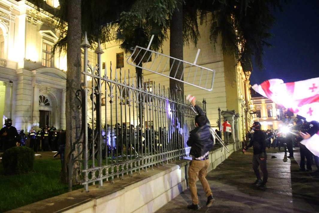 Протестующий бросает заграждение, пытаясь прорваться на территорию президентского дворца во время митинга оппозиции