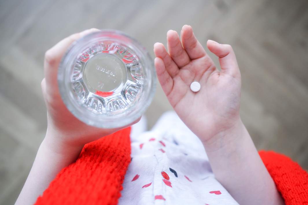 Девушка с таблеткой и стаканом воды